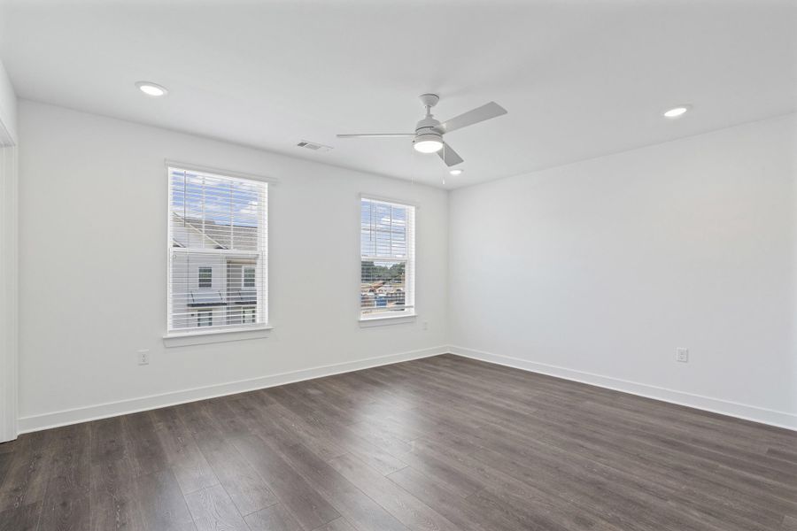White walls, wood-finish flooring, recessed lighting, ceiling fan, and two windows with blinds