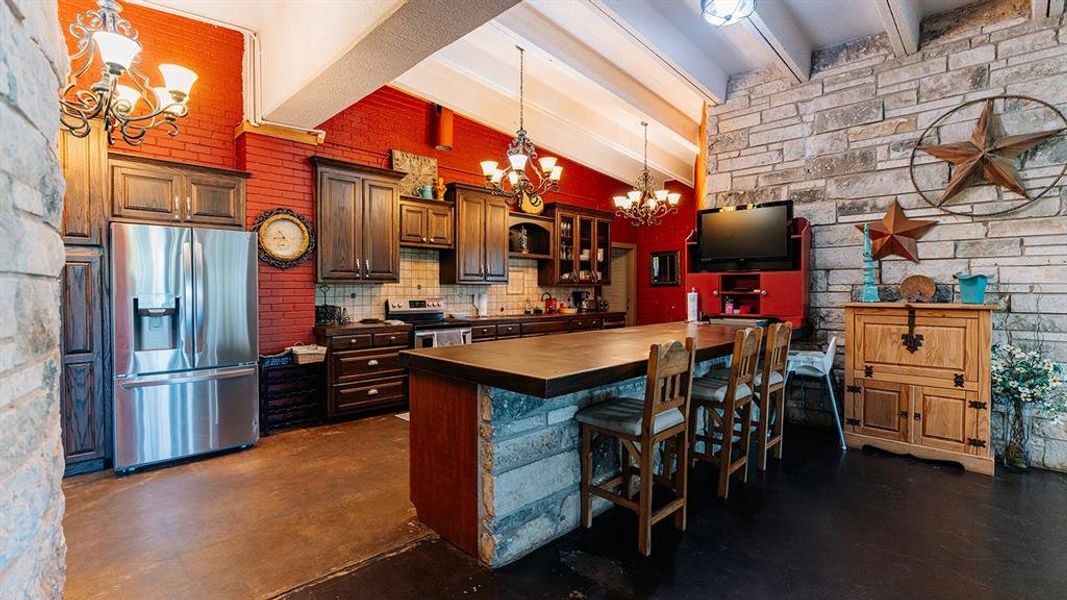 Kitchen featuring a breakfast bar, beamed ceiling, appliances with stainless steel finishes, a chandelier, and glass insert cabinets