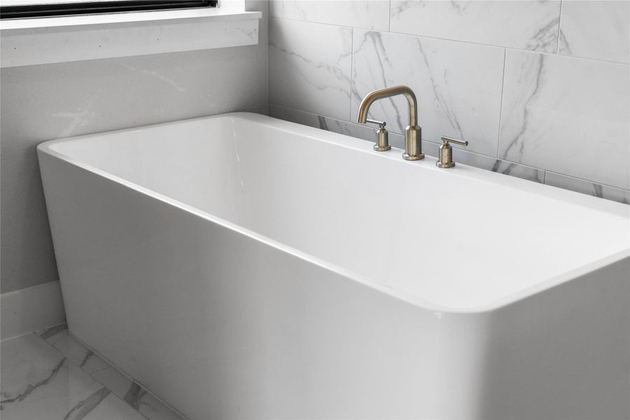 Indulge in the primary bath's deep, built-in soaking tub with elegant chrome fixtures and a sleek tile surround for a true spa-like retreat.