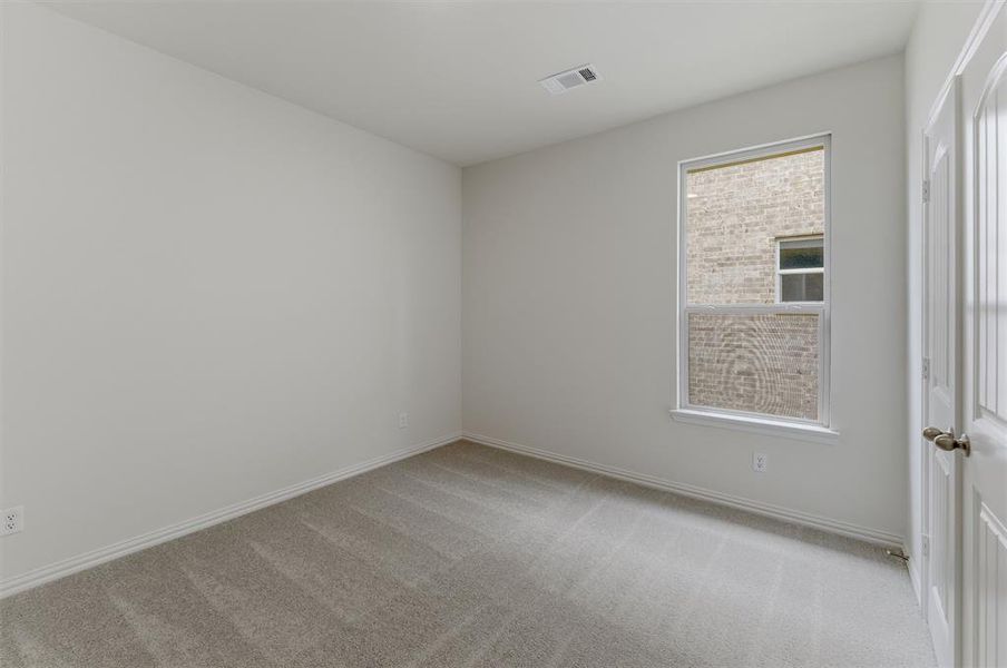 Spacious room featuring neutral carpeting, light-toned walls, and a white trim package