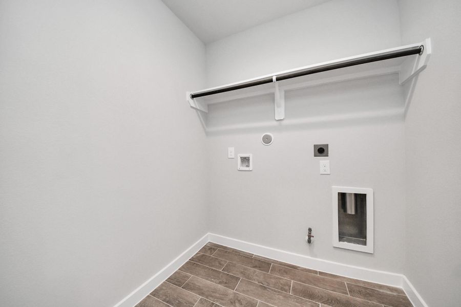 A perfect blend of functionality and comfort. Capture the essence of easy living with a first-floor laundry room, thoughtfully equipped with shelving for effortless organization. Both electric and gas connections available. Sample photo of completed home with similar floor plan. Actual colors and selections may vary.