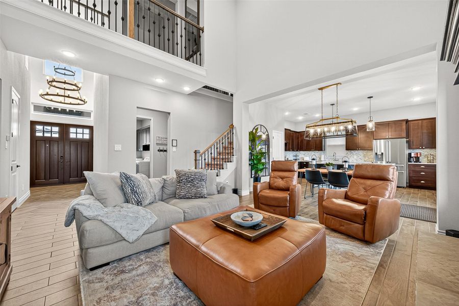 Expansive great room with wood-look tile flooring and dramatic ceilings, seamlessly connecting to the foyer and kitchen for effortless entertaining. Expansive great room with wood-look tile flooring and dramatic ceilings, seamlessly connecting to the foyer and kitchen for effortless entertaining.