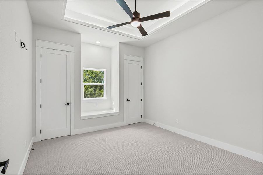 Carpeted spare room with a raised ceiling and a ceiling fan Carpeted spare room with a raised ceiling and a ceiling fan