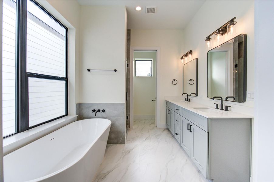 Luxurious primary bathroom featuring a sleek soaking tub, dual vanities with elegant fixtures, and abundant natural light. Luxurious primary bathroom featuring a sleek soaking tub, dual vanities with elegant fixtures, and abundant natural light.