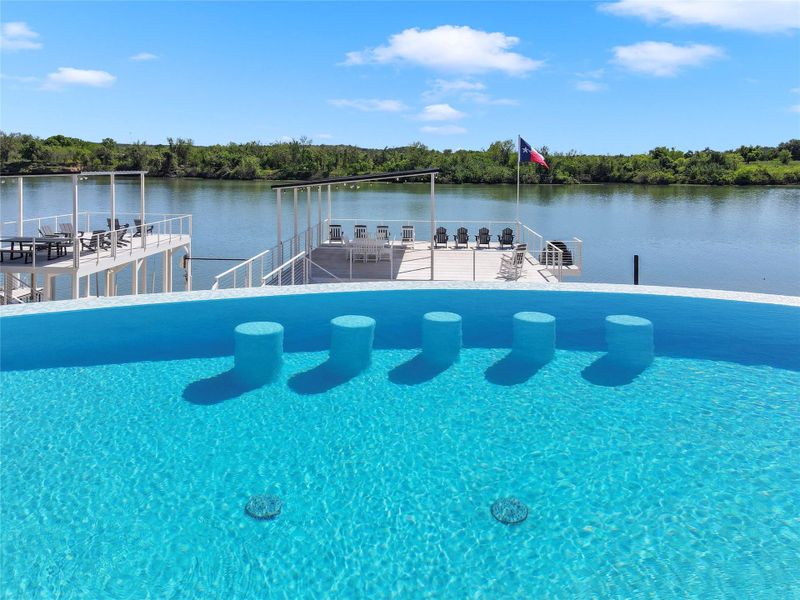 An infinity edge pool overlooks private boat docks along the scenic riverfront.
