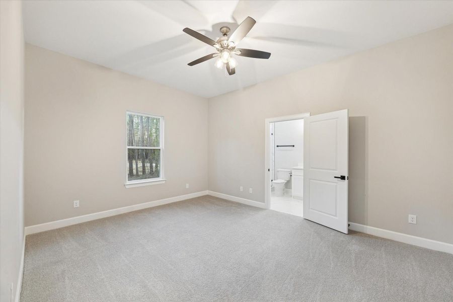 fourth bedroom with carpeted flooring and full bath with frameless shower. Window looks to the side of the home.