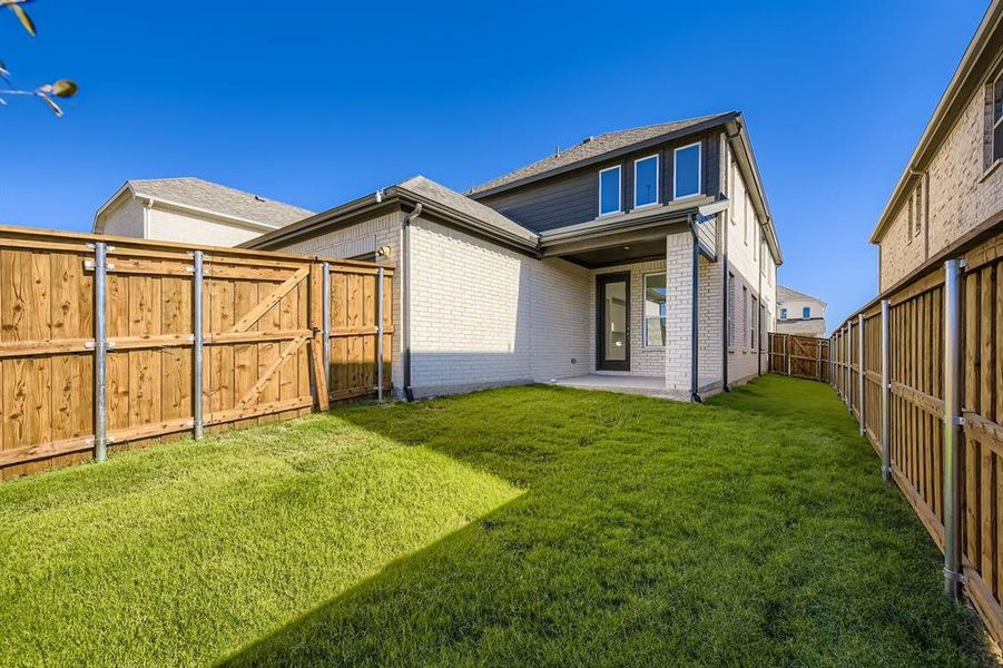 Back of house featuring brick siding, a fenced backyard, a patio area, and a gate