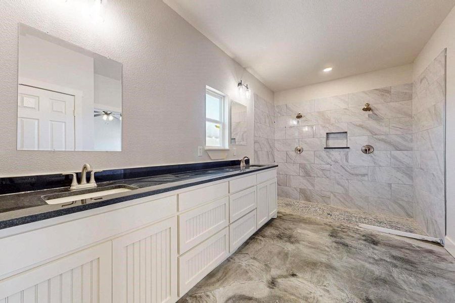 Full bath featuring double vanity, walk in shower, and a sink