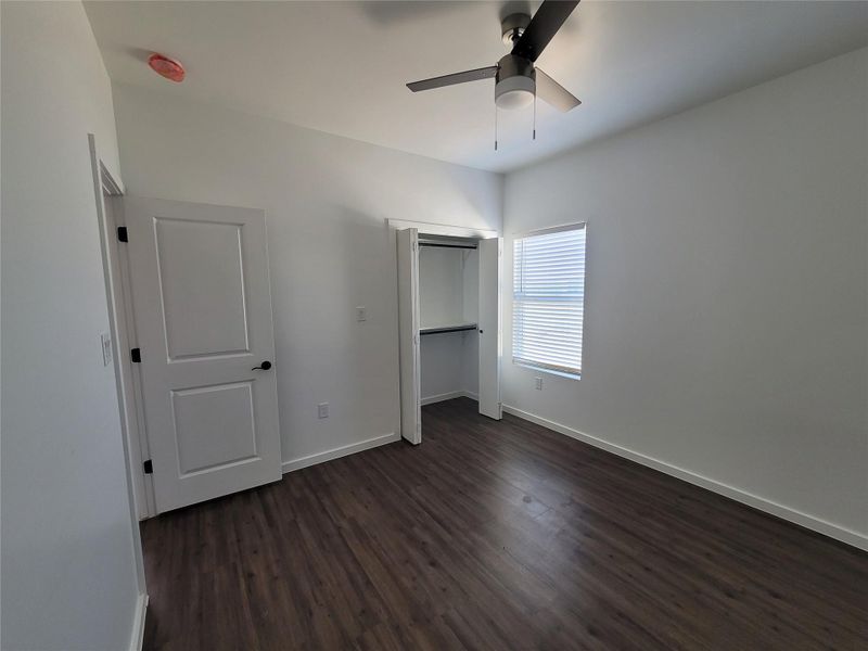 An inviting room awaits, featuring rich hardwood floors and a modern ceiling fan for comfort.