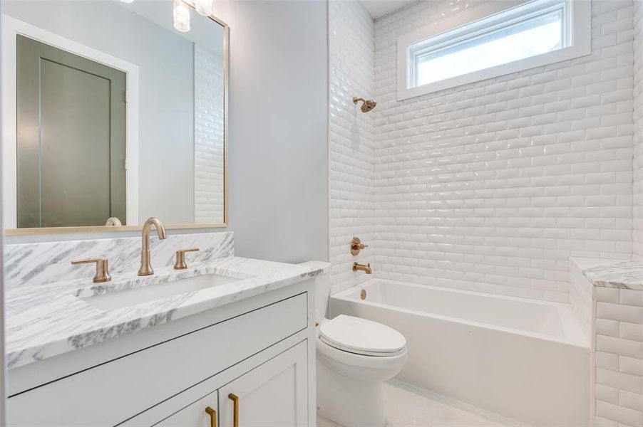 Full bathroom featuring toilet, vanity, and tiled shower / bath