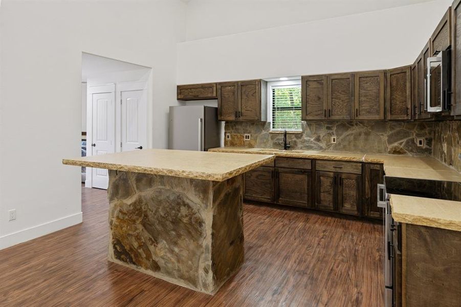 Kitchen featuring dark wood-type flooring, appliances with stainless steel finishes, a kitchen island, and sink