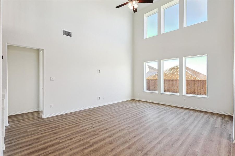 Unfurnished living room featuring ceiling fan, a high ceiling, and light hardwood / wood-style floors