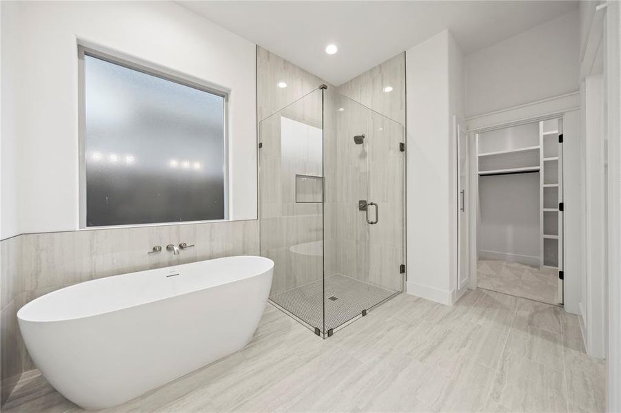 Full bathroom with a shower stall, a soaking tub, a walk in closet, recessed lighting, and tile walls