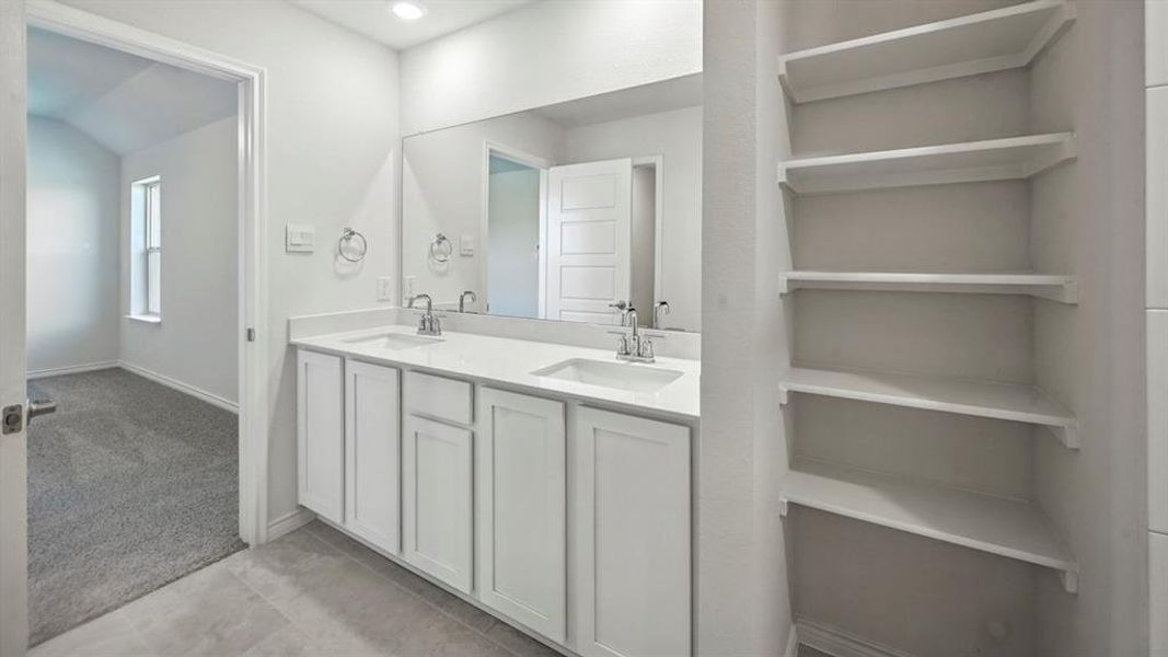 Dual vanity with white cabinetry, integrated sinks, chrome fixtures, and a large wall mirror Dual vanity with white cabinetry, integrated sinks, chrome fixtures, and a large wall mirror