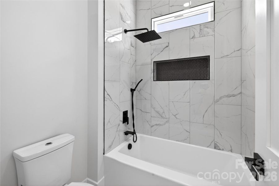 This is not your average guest bathroom — the floor-to-ceiling tile and designer finishes make it feel so much more elevated
