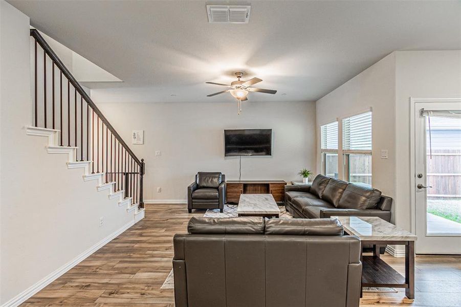 Living area featuring visible vents, a ceiling fan, wood finished floors, stairway, and baseboards