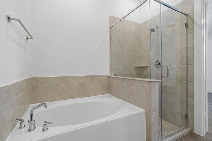 This primary bathroom is designed as a relaxing oasis, featuring a sought-after separate soaking tub and a spacious glass-enclosed walk-in shower.