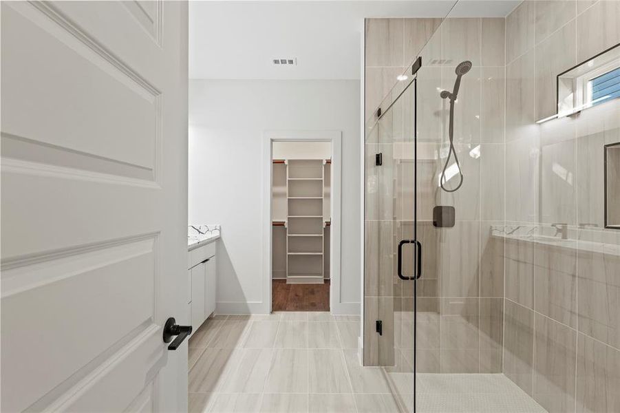 Full bath with vanity, baseboards, visible vents, a stall shower, and a walk in closet