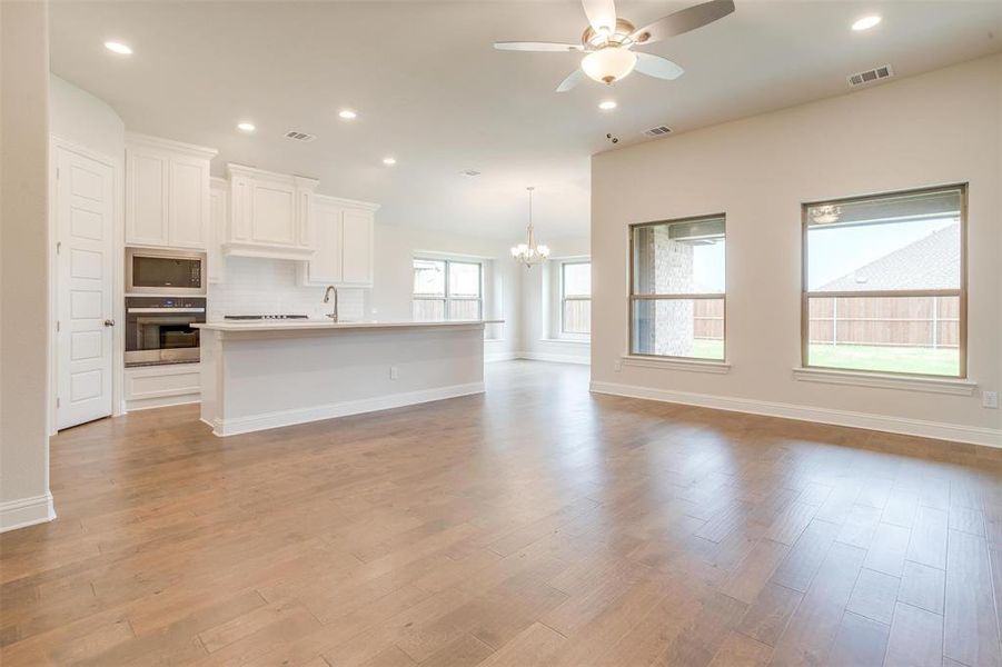 Kitchen featuring white cabinetry, backsplash, a kitchen island with sink, black microwave, and oven