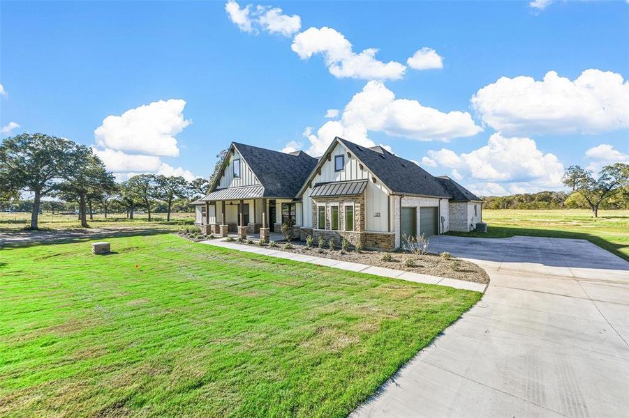 View of front of house featuring a front lawn, covered porch, and a garage