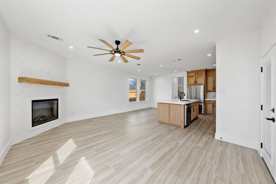 Kitchen with open floor plan, light countertops, an island with sink, and visible vents