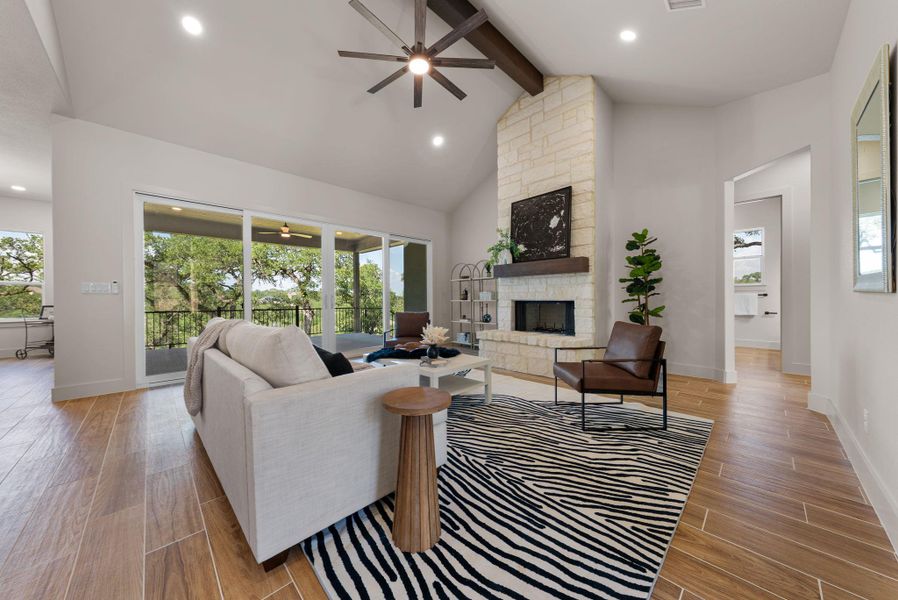 Natural light pours into this living space, featuring a stone fireplace and access to a private balcony overlooking green trees.