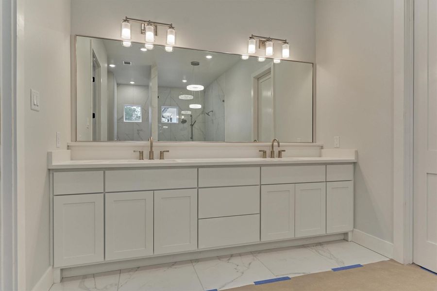 Elegant double-vanity in the primary suite, featuring clean shaker cabinetry, brushed nickel fixtures, and an expansive mirror that enhances the spa-like atmosphere.
