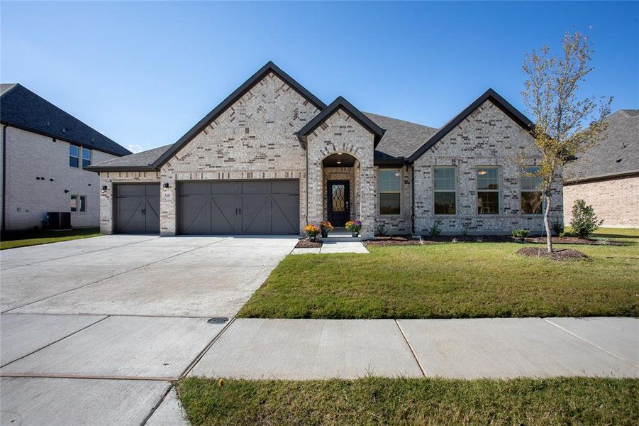 French provincial home featuring central air condition unit, a front yard, and a garage