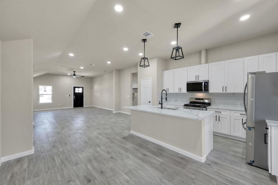 Wide-angle view of the expansive living and dining area, perfectly designed for entertaining with seamless flow from the kitchen to the back entryway.