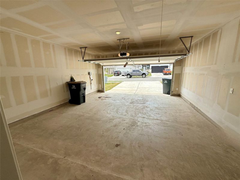 Spacious two-car garage with concrete flooring, automatic garage door opener, and unfinished drywall walls