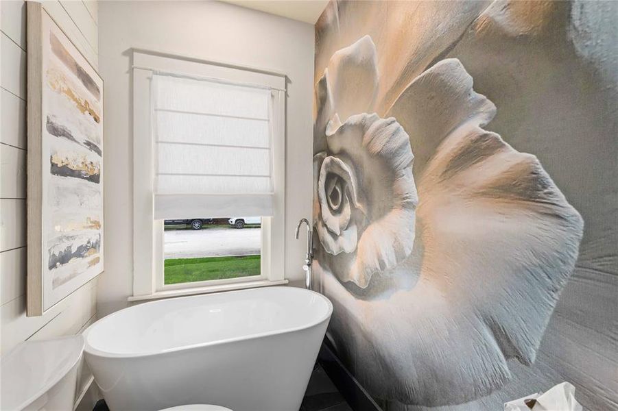 Freestanding soaking tub with a floor-mounted faucet, complemented by a large-scale floral wall mural
