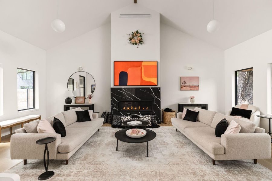 A striking black marble fireplace with a mounted television serves as the central focus in this inviting living room. A striking black marble fireplace with a mounted television serves as the central focus in this inviting living room.