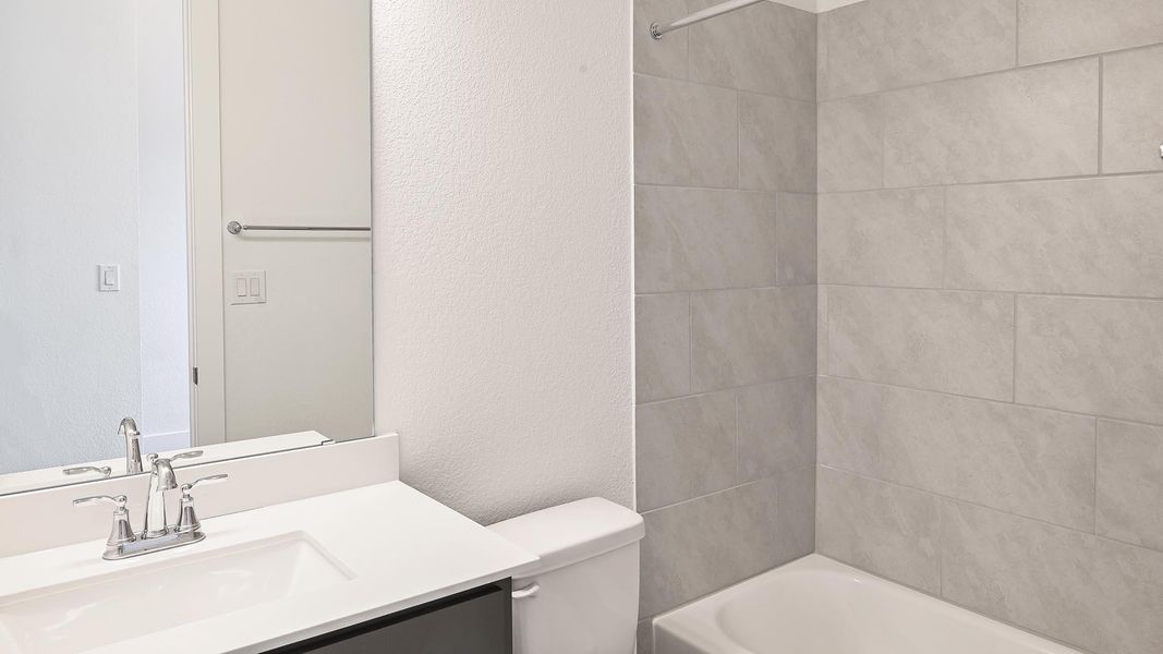 Full bath with a textured wall, vanity, and bathing tub / shower combination Full bath with a textured wall, vanity, and bathing tub / shower combination