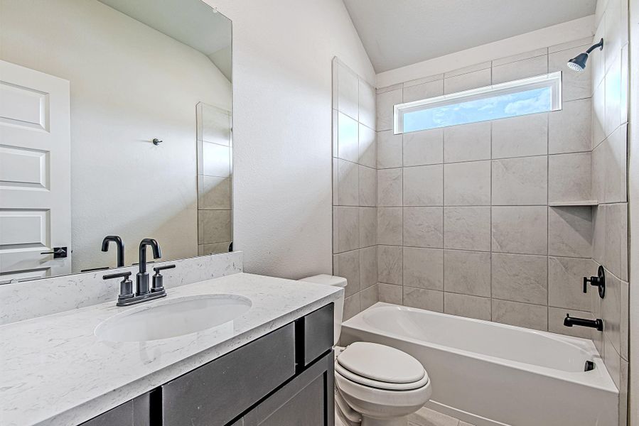 Upstairs bathroom with soft neutral tile, quartz countertops, and stylish black hardware—perfectly placed between secondary bedrooms.