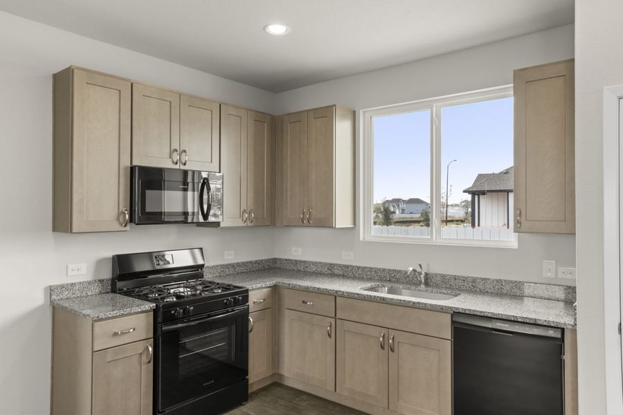 Image of kitchen with a stove and countertops with cabinets and a window over the sink