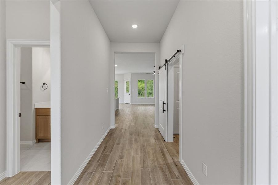 Hall with wood tiled floors, a barn door, and recessed lighting