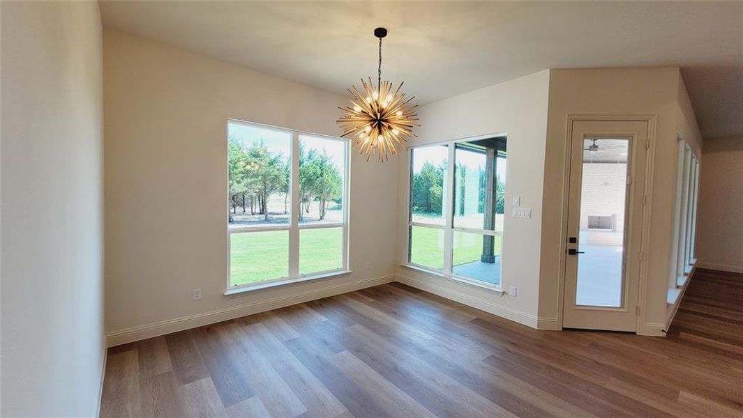 Spacious room featuring wood-finish flooring, a modern sputnik-style chandelier, and multiple large windows