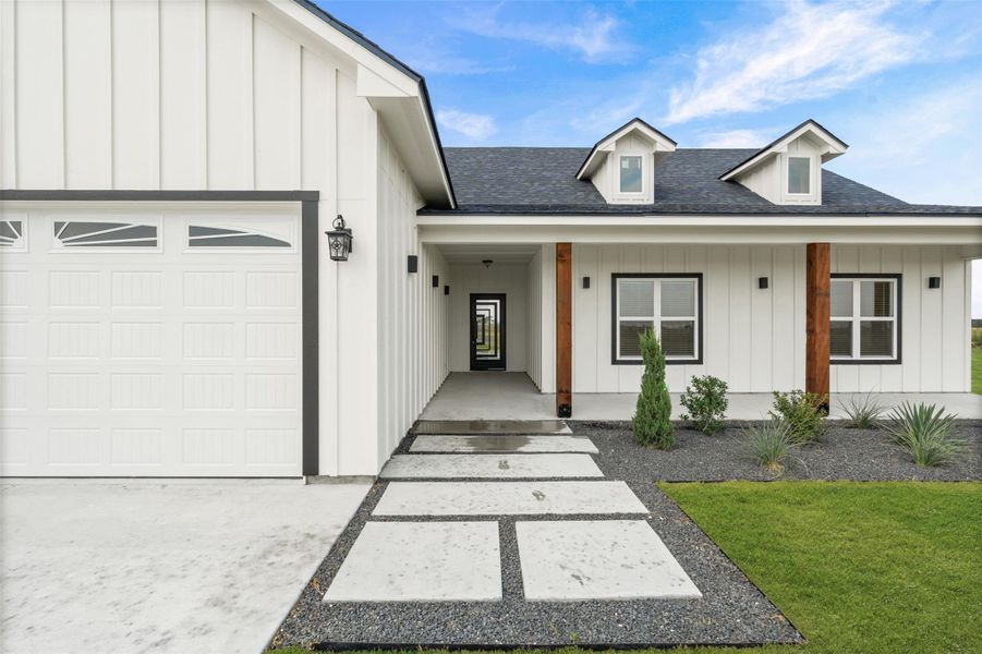 Modern vertical siding and clean concrete pavers create a welcoming, contemporary facade.