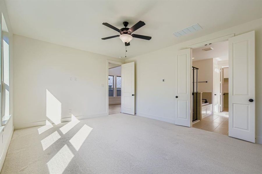 Unfurnished bedroom with light carpet, ceiling fan, and connected bathroom