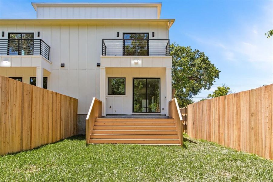 Rear view of house with a balcony and a lawn