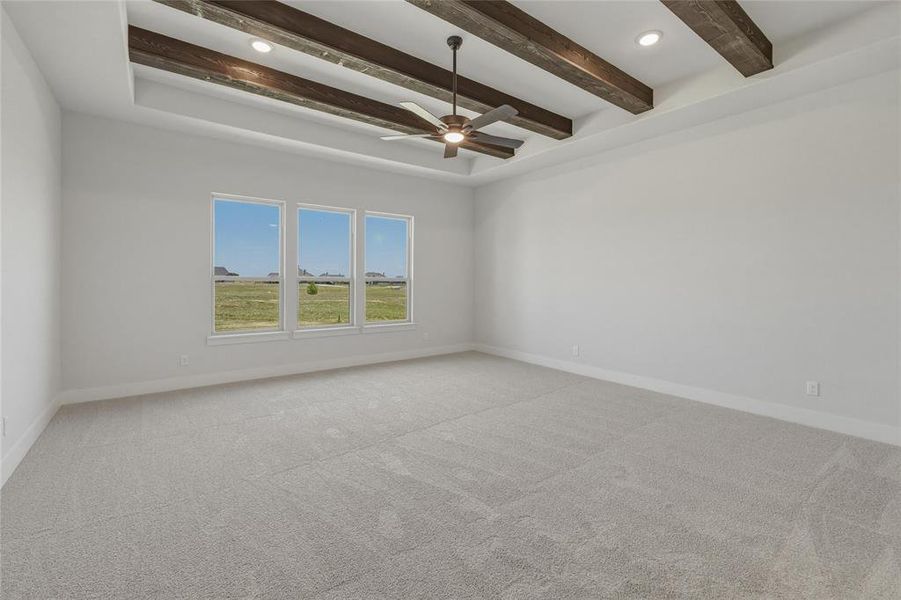 Spacious room featuring a tray ceiling with exposed wood beams and recessed lighting Spacious room featuring a tray ceiling with exposed wood beams and recessed lighting