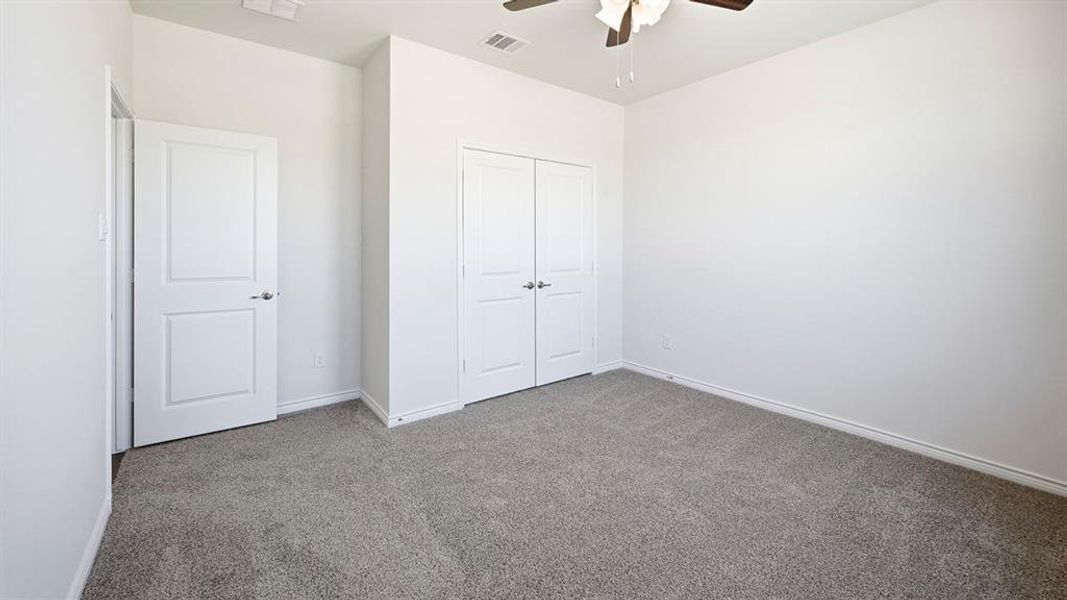 Unfurnished bedroom with carpet, a closet, and a ceiling fan