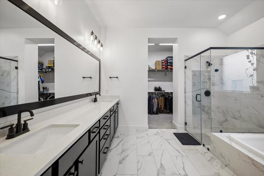 The spa-like primary bathroom showcases dual vanities with quartz countertops, oversized framed mirrors, elegant lighting, and a beautifully designed walk-in shower. The spa-like primary bathroom showcases dual vanities with quartz countertops, oversized framed mirrors, elegant lighting, and a beautifully designed walk-in shower.