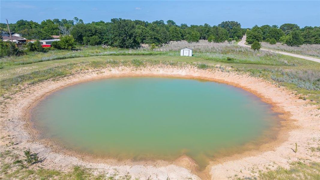 Expansive property featuring a large pond and a clear blue sky overhead Expansive property featuring a large pond and a clear blue sky overhead