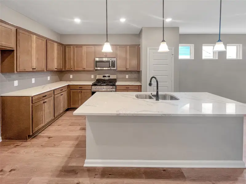 The Oakshire II- Kitchen with Quartz Countertops and Island. Home under construction.  Sample image for illustration; upgrades, options, and colors may vary.