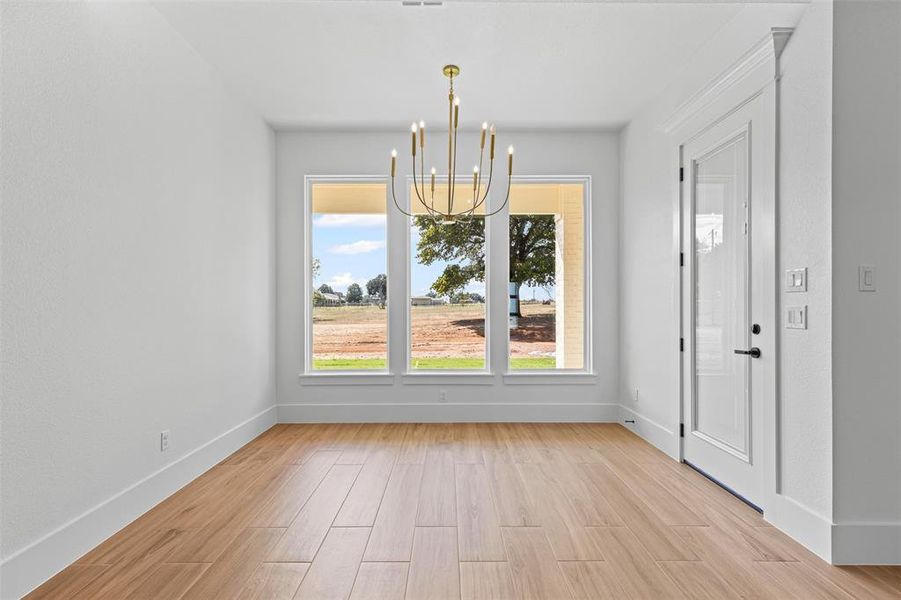 Unfurnished dining area featuring a chandelier and light wood-style flooring