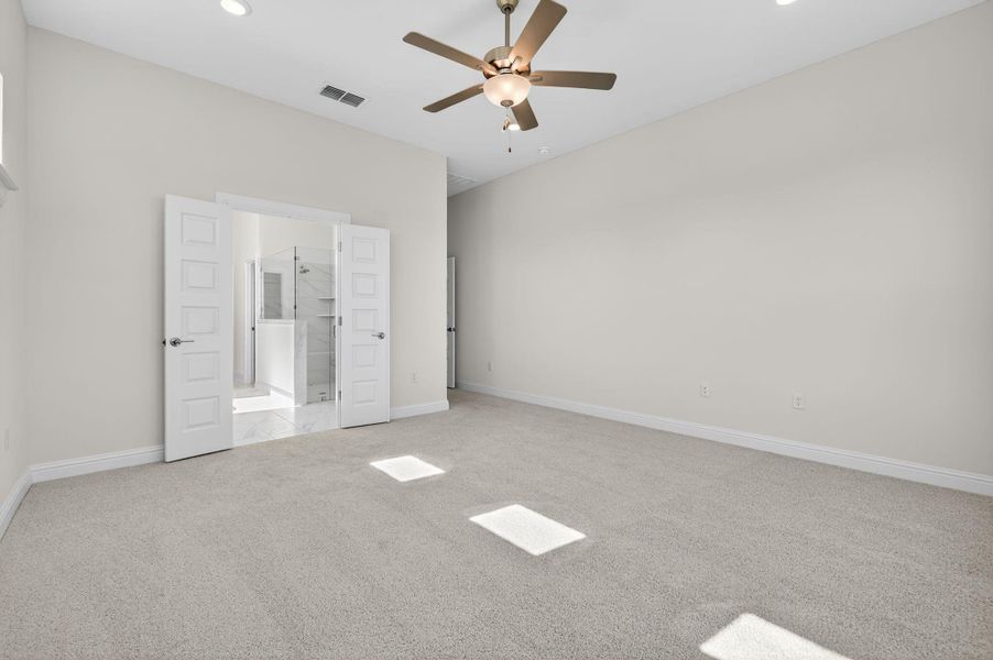 Unfurnished bedroom with light colored carpet, ceiling fan, ensuite bathroom, and recessed lighting