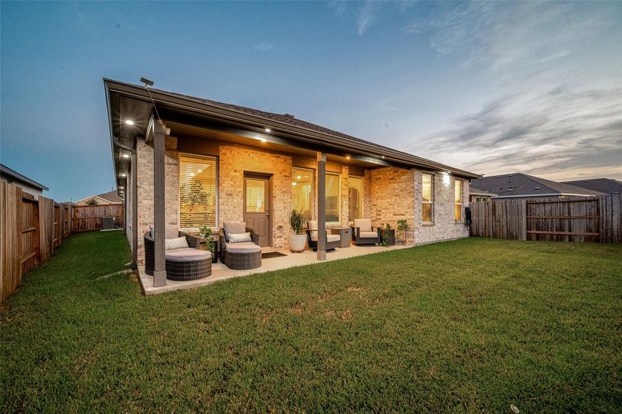Evening view of the backyard and covered patio. Evening view of the backyard and covered patio.