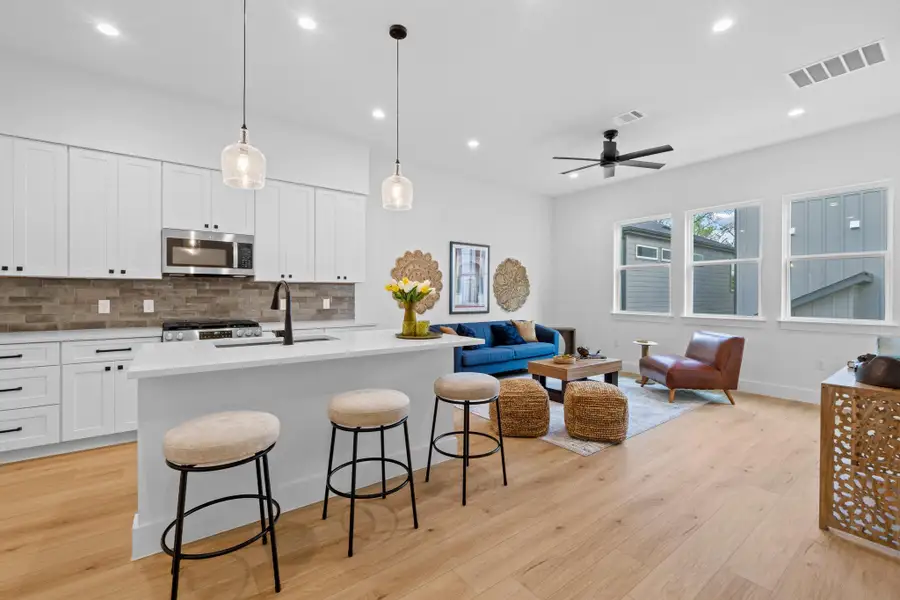 Kitchen featuring open floor plan, tasteful backsplash, a kitchen island with sink, hanging light fixtures, and a breakfast bar