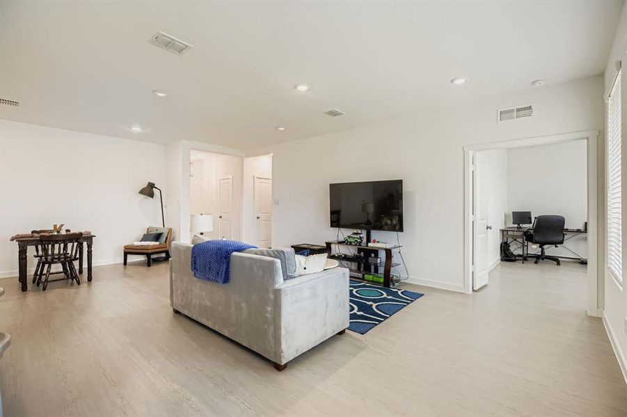 Living room with an office area, light wood-style floors, and recessed lighting